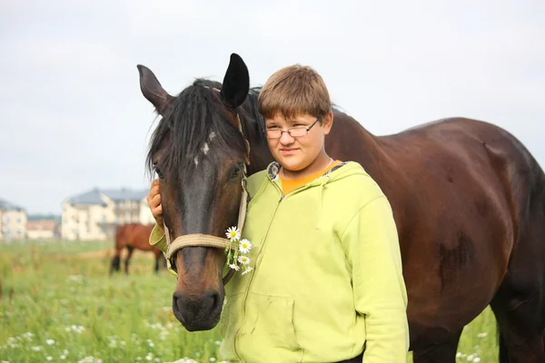 Smiling teenager boy with horses at the field — Stock Photo, Image