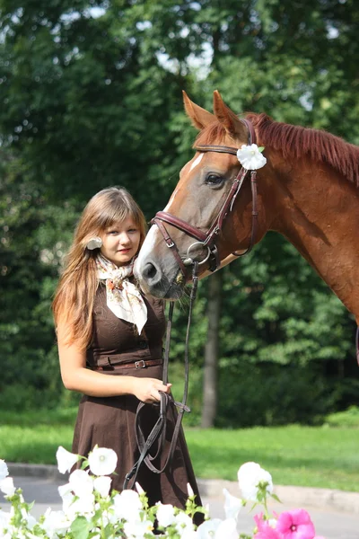 Schönes Mädchen in Kleid und Pferdeporträt in der Nähe des Blumenbeetes — Stockfoto