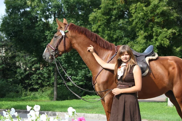 Beautiful girl in dress and horse portrait near the flower bed — Stock Photo, Image