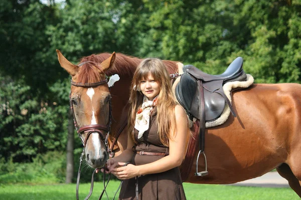 Hermosa chica en vestido y retrato de caballo cerca de la cama de flores — Foto de Stock