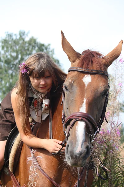 Hermosa chica adolescente a caballo en el campo de las flores — Foto de Stock