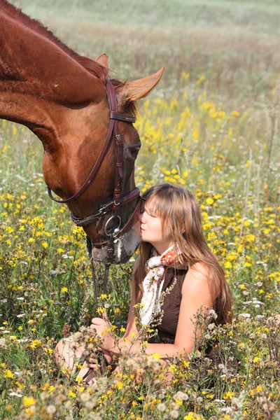 地面と栗の馬立っている近くに座っている女の子 — ストック写真