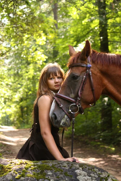 Beautiful girl and brown horse portrait in mysterious forest — Stock Photo, Image