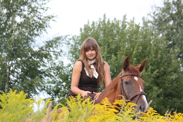Menina adolescente bonita equitação cavalo no campo das flores — Fotografia de Stock