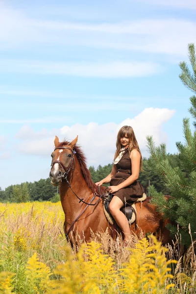 Vacker tonåring flicka Rider häst på fältet av blommor — Stockfoto