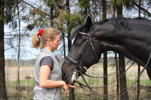 若いブロンドの女性と笑みを浮かべて黒い馬 — ストック写真