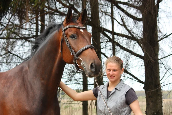 Joven rubia y caballo de la bahía juntos — Foto de Stock