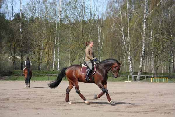 Mujer rubia montando caballo de bahía — Foto de Stock