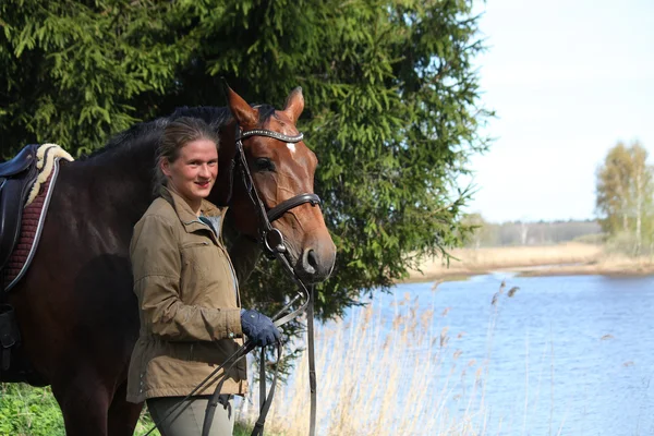 Giovane donna e cavallo marrone insieme sulla costa del fiume — Foto Stock