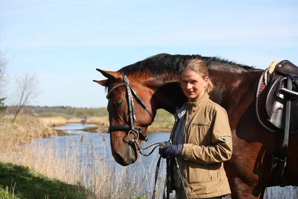 Giovane donna e cavallo marrone insieme sulla costa del fiume — Foto Stock