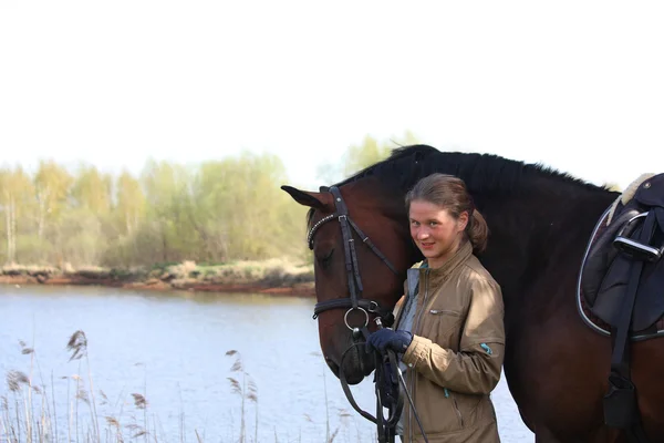 Mujer joven y caballo marrón juntos en la costa del río —  Fotos de Stock