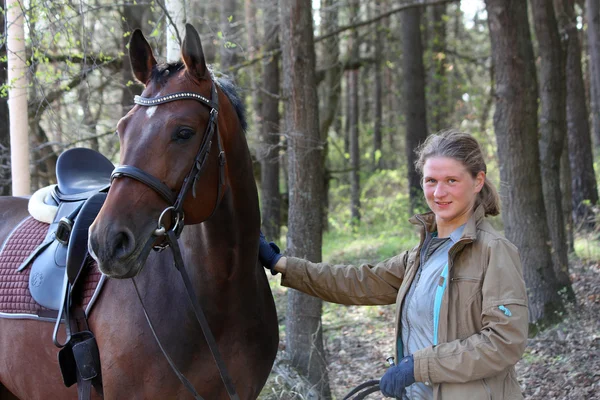 Jovem mulher e cavalo marrom juntos na floresta — Fotografia de Stock