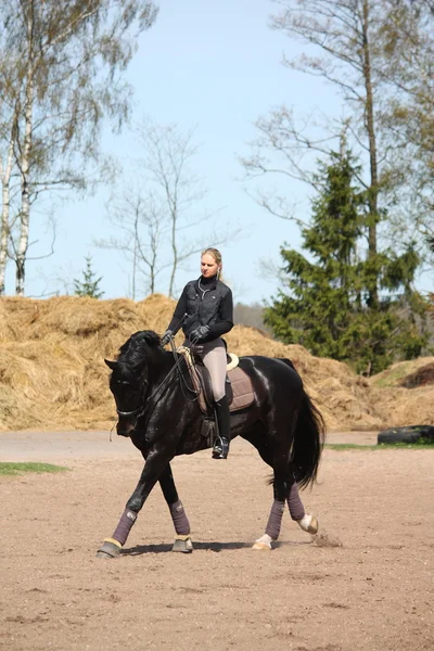 Mulher loira montando cavalo preto — Fotografia de Stock