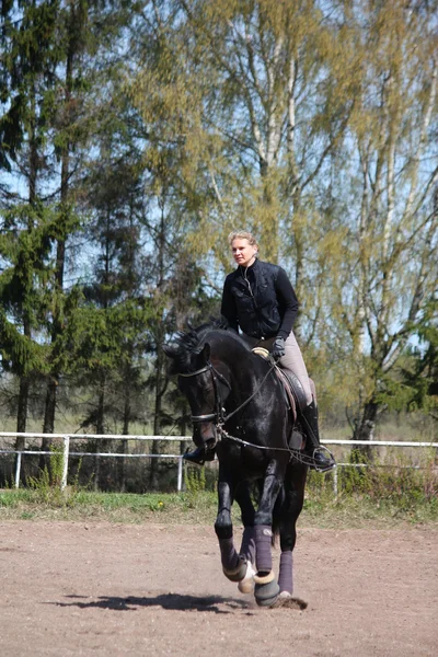 Mujer joven montando caballo negro — Foto de Stock