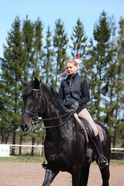 Blondine und schwarzes Pferd — Stockfoto