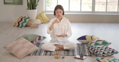 Evde meditasyon yapan genç bir kadın.