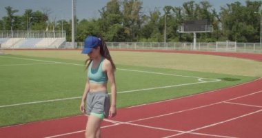 Sportif genç bayan stadyumda koşmadan önce ısınıyor.