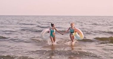 Deniz kıyısında yüzme yüzükleri olan güzel genç kadınlar.