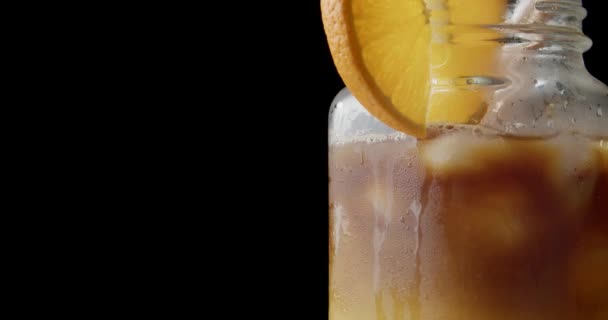 黒を背景にオレンジジュースとおいしいコーヒーのメイソン瓶 クローズアップ — ストック動画