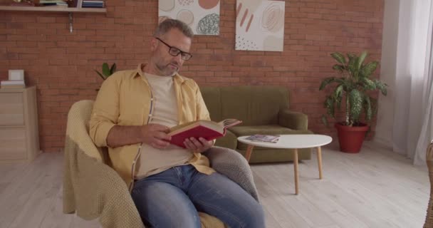 Reifer Mann Mit Buch Und Seiner Kleinen Enkelin Hause — Stockvideo
