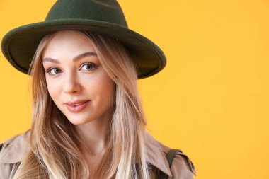 Sarı arka planda keçeli şapkalı genç kadın portresi