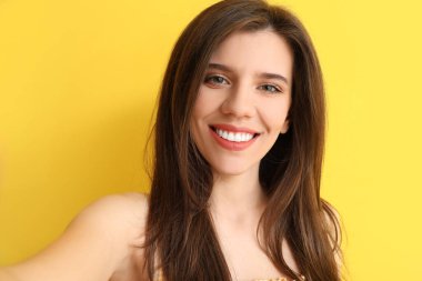 Renkli arka planda selfie çeken zarif genç bir kadın.