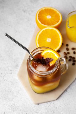 Mason kavanozu dolusu lezzetli kahve, portakal suyu ve hafif arka planda malzemeler.