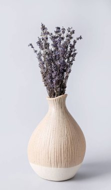 Gri arka planda güzel lavanta çiçekleri olan vazo