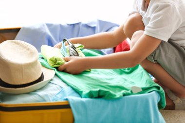 Küçük çocuk evde bavulunu topluyor, yakın plan.