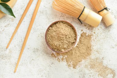 Hojicha pudralı kase ve açık arkaplanda chasen.