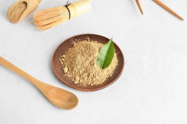 Beyaz arka planda hojicha tozu ve kaşık tabağı