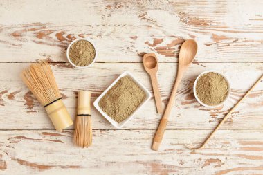 Beyaz ahşap arka planda hojicha tozu, chasen, chashaku ve kaşıklarla dolu kaseler.