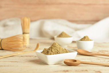 Beyaz ahşap arka planda hojicha pudrası ve kaşıkla kase