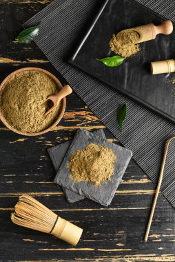 Siyah ahşap arka planda hojicha tozu, chasen ve chashaku karışımı.
