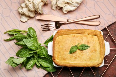 Lezzetli mantarlı turta ve arkaplandaki malzemelerle pişirme yemeği.