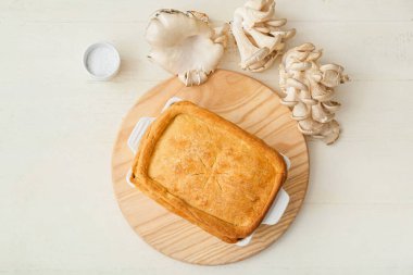 Beyaz ahşap zemin üzerinde lezzetli mantarlı turta pişirme tabağı