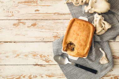 Beyaz ahşap zemin üzerinde lezzetli mantarlı turta pişirme tabağı