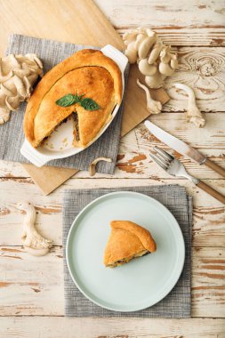 Beyaz ahşap arka planda lezzetli mantarlı yemek ve tabak.