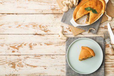 Beyaz ahşap arka planda lezzetli mantarlı yemek ve tabak.