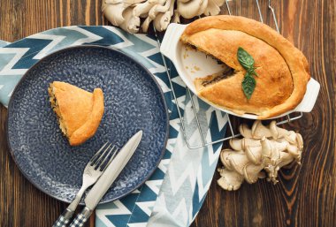 Ahşap arka planda lezzetli mantarlı yemek ve tabak.