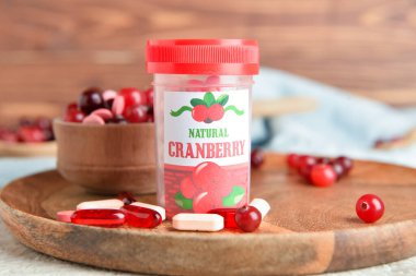 Ahşap tepside bir şişe yabanmersini hapı.