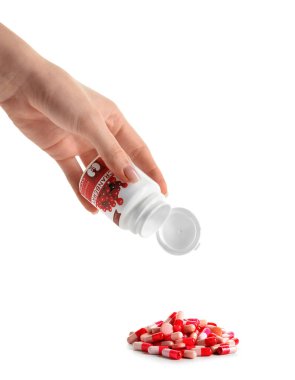 Şişeli bir kadın eli ve beyaz arka planda bir yığın yabanmersini hapı.