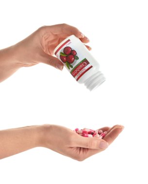 Şişeli kadın elleri ve beyaz arka planda kızılcık hapları.