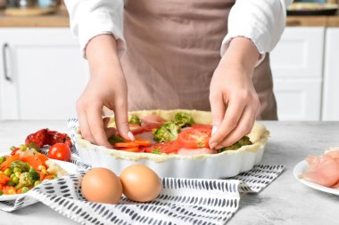 Mutfak masasında sebzeli tavuk turtası hazırlayan kadın, yakın plan.