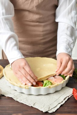 Mutfak masasında sebzeli tavuk turtası hazırlayan kadın, yakın plan.