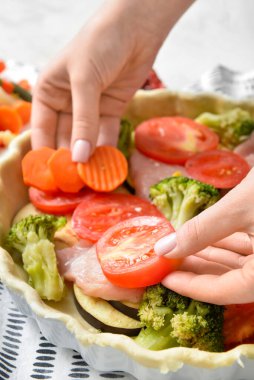 Hafif arka planda sebzeli tavuk güveci hazırlayan kadın, yakın plan.