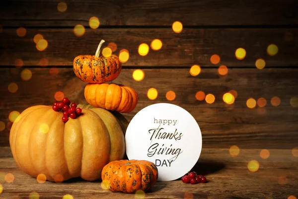 Şükran Günü için güzel bir tebrik kartı. Ahşap arka planda balkabakları ve bulanık ışıkları var.