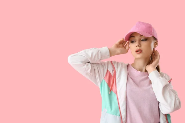 在粉色背景上摸棒球帽的女人 — 图库照片