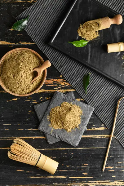 Siyah ahşap arka planda hojicha tozu, chasen ve chashaku karışımı.