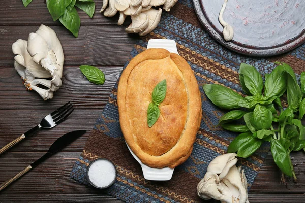 Lezzetli mantarlı kek ve siyah ahşap arka planda malzemeler.